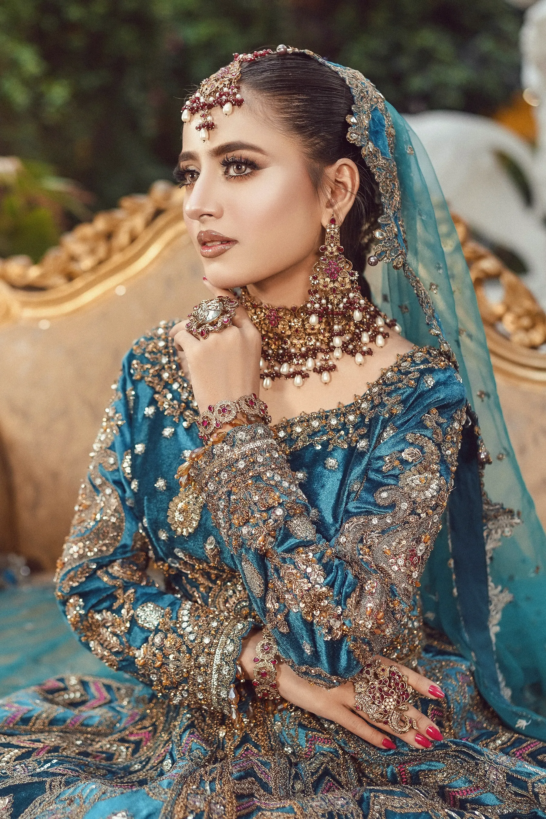 A bride in teal and gold with an embroidered dupatta