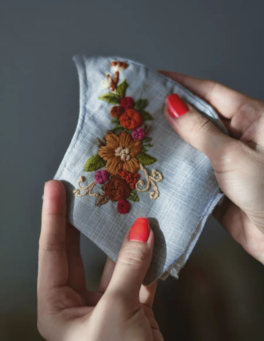 Hands holding fabric embroidered with flowers